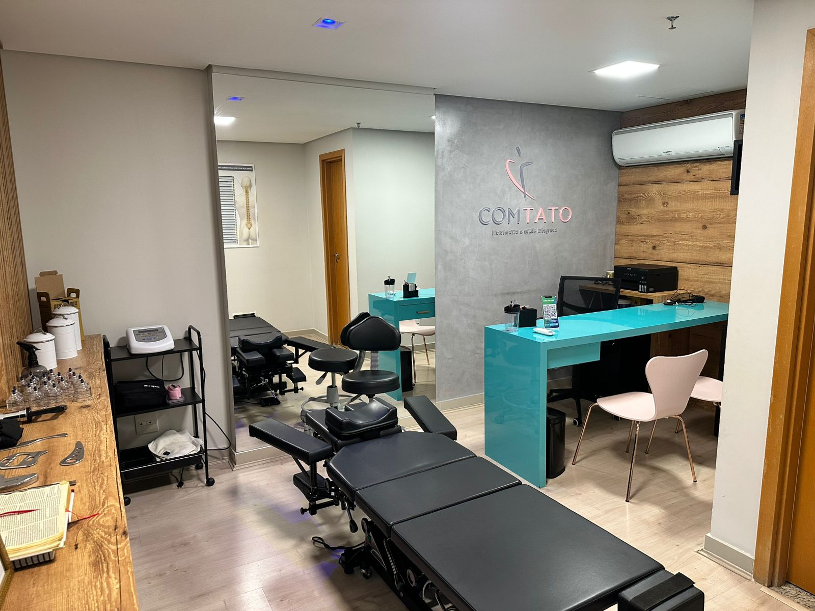 Recepção da clínica ComTato com logo na parede e balcão turquesa